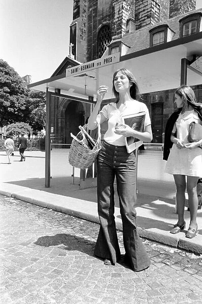 actress-jane-birkin-shopping-paris-21363578.jpg Streetstyle shot of actress Jane Birkin wearing denim flare leg jeans and carrying a basket, posing on the streets in France.